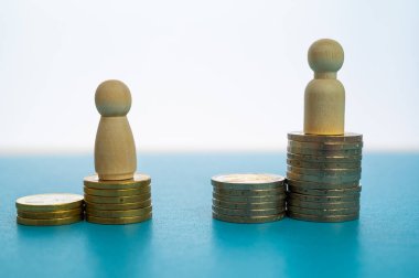 Kadınlar ve erkekler arasındaki iş yerinde eşit ücret kavramı. Bozuk para yığınları üzerinde tahta figürler.