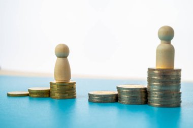 Kadınlar ve erkekler arasındaki iş yerinde eşit ücret kavramı. Bozuk para yığınları üzerinde tahta figürler.