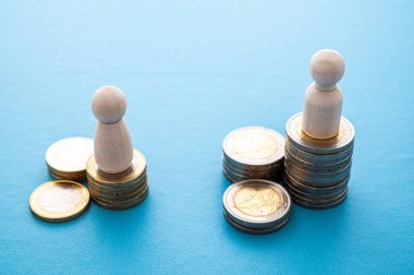 Kadınlar ve erkekler arasındaki iş yerinde eşit ücret kavramı. Bozuk para yığınları üzerinde tahta figürler.