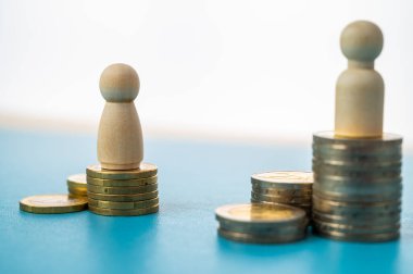 Kadınlar ve erkekler arasındaki iş yerinde eşit ücret kavramı. Bozuk para yığınları üzerinde tahta figürler.
