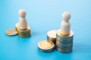 Kadınlar ve erkekler arasındaki iş yerinde eşit ücret kavramı. Bozuk para yığınları üzerinde tahta figürler.
