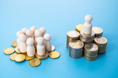 Tahta figürler, bozuk para yığınları, servet dağılımı konsepti. Çok az insan servetin çoğunu elinde tutar..