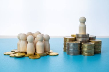 Kadınlar ve erkekler arasındaki iş yerinde eşit ücret kavramı. Bozuk para yığınları üzerinde tahta figürler.