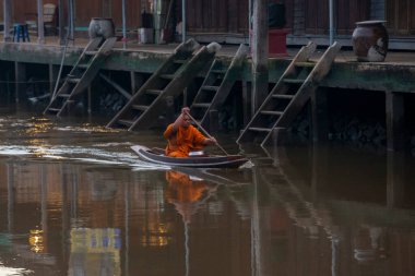 Bir Budist keşiş, Tayland, Tayland, Amphawa 'da Samut Songkhram şehrindeki Mae Klong Nehri' nin Klong Chula 'sındaki bir orman teknesindeki evleri ziyaret ederek sadaka topluyor.