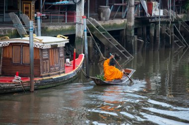 Bir Budist keşiş, Tayland, Tayland, Amphawa 'da Samut Songkhram şehrindeki Mae Klong Nehri' nin Klong Chula 'sındaki bir orman teknesindeki evleri ziyaret ederek sadaka topluyor.