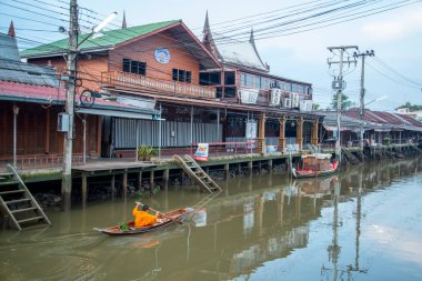 Bir Budist keşiş, Tayland, Tayland, Amphawa 'da Samut Songkhram şehrindeki Mae Klong Nehri' nin Klong Chula 'sındaki bir orman teknesindeki evleri ziyaret ederek sadaka topluyor.