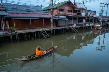 Bir Budist keşiş, Tayland, Tayland, Amphawa 'da Samut Songkhram şehrindeki Mae Klong Nehri' nin Klong Chula 'sındaki bir orman teknesindeki evleri ziyaret ederek sadaka topluyor.