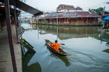 Bir Budist keşiş, Tayland, Tayland, Amphawa 'da Samut Songkhram şehrindeki Mae Klong Nehri' nin Klong Chula 'sındaki bir orman teknesindeki evleri ziyaret ederek sadaka topluyor.