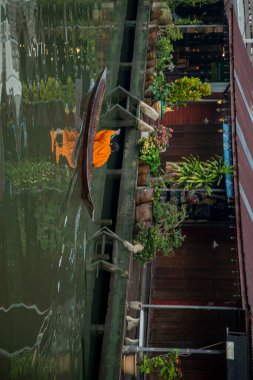Bir Budist keşiş, Tayland, Tayland, Amphawa 'da Samut Songkhram şehrindeki Mae Klong Nehri' nin Klong Chula 'sındaki bir orman teknesindeki evleri ziyaret ederek sadaka topluyor.