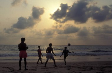 Çocuklar Hindistan, Hindistan, Goa, Goa, Nisan 1996 'da Vagator şehrinde peyzaj ve sahil ile kumlu bir plajda futbol oynarlar.