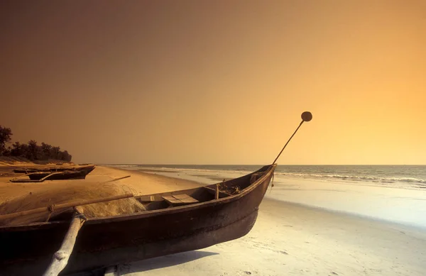 stock image a  wood fishingboat at a sandy Beach with Landscape and Coast at the Town of Vagator in the Province of Goa in India,  India, Goa, April, 1996