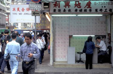 Hong Kong 'un Hong Kong şehrindeki merkezi Hong Kong' da mülk reklamları, evler ve odalar olan bir duvarın önündeki insanlar. Çin, Hong Kong, Mayıs 1997