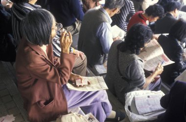 İnsanlar Hongkong yakınlarındaki Sha Tin 'de bir at yarışı stadyumunda at yarışı oynandığına dair iddiaya girdiler. Çin, Hong Kong, Mayıs 1997