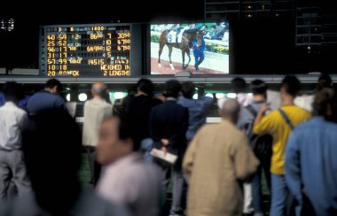 İnsanlar Hongkong yakınlarındaki Sha Tin 'de bir at yarışı stadyumunda at yarışı oynandığına dair iddiaya girdiler. Çin, Hong Kong, Mayıs 1997