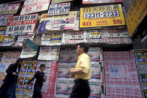 Stock image people in front of a wall with property advertising and ads of Property, Homes and Rooms in Central Hongkong in the city of Hongkong in Hongkong.  China, Hongkong, May, 1997