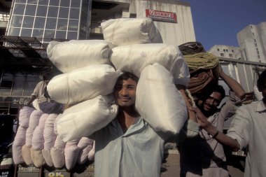 Hindistan 'ın Gujarat eyaletindeki Surat şehrindeki ticaret pazarında insanlar Cotton' la birlikte çanta taşıyorlar. Hindistan, Gujarat, Nisan 1998