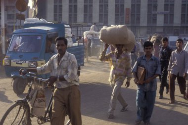 Hindistan 'ın Gujarat eyaletindeki Surat şehrindeki ticaret pazarında insanlar Cotton' la birlikte çanta taşıyorlar. Hindistan, Gujarat, Nisan 1998