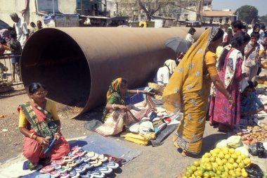 Hindistan 'ın Gujarat eyaletindeki Surat şehrindeki gıda pazarında büyük bir su borusunun önünde insanlar var. Hindistan, Gujarat, Nisan 1998