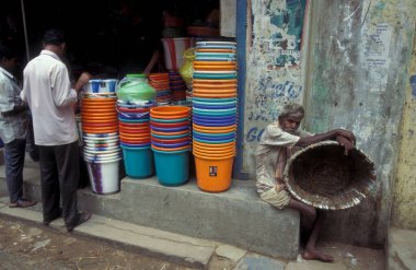 Hindistan 'ın Tamil Nadu ilindeki Chennai şehrinde bir pazar caddesinde plastik kova dükkanı ve doğal kovalı adamlar. Hindistan, Chennai, Nisan 1998