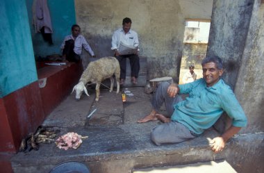 Hindistan 'ın Tamil Nadu ilindeki Chennai şehrindeki bir gıda pazarında bir koyunla kasap. Hindistan, Chennai, Nisan 1998