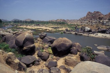 Hindistan 'ın Karnataka eyaletindeki Hampi şehrinin tipik taşları ve tepeleriyle manzara ve nehir.. 