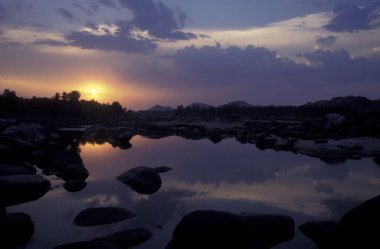 Hindistan 'ın Karnataka eyaletindeki Hampi şehrinin tipik taşları ve tepeleriyle manzara ve nehir.. 