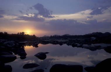 Hindistan 'ın Karnataka eyaletindeki Hampi şehrinin tipik taşları ve tepeleriyle manzara ve nehir.. 