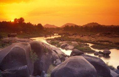 Hindistan 'ın Karnataka eyaletindeki Hampi şehrinin tipik taşları ve tepeleriyle manzara ve nehir.. 