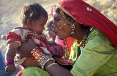 Hindistan 'ın Rajasthan ilindeki Jaisalmer kasabasında bebeğiyle birlikte bir Rajasthani kadının portresi. Hindistan, Jaisalmer, Ocak 1998
