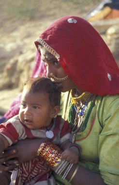 Hindistan 'ın Rajasthan ilindeki Jaisalmer kasabasında bebeğiyle birlikte bir Rajasthani kadının portresi. Hindistan, Jaisalmer, Ocak 1998