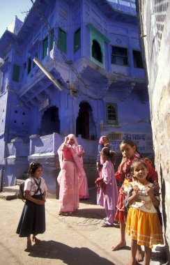 Mavi Şehir 'deki mavi boyanmış bir evin ve Hindistan' ın Rajasthan eyaletindeki Jodhpur kasabasının önünde yaşayan insanlar. Hindistan, Jodhpur, Ocak 1998