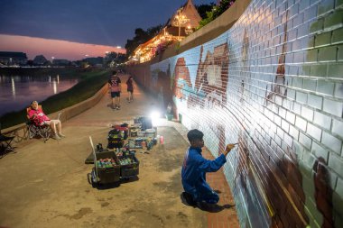 Sanatçı, Tayland 'ın kuzeyindeki Phitsanulok ili ve Nan Nehri' nde duvar boyuyor. Tayland, Phitsanulok, Kasım 29, 2024.