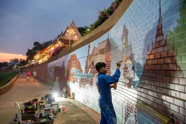 Sanatçı, Tayland 'ın kuzeyindeki Phitsanulok ili ve Nan Nehri' nde duvar boyuyor. Tayland, Phitsanulok, Kasım 29, 2024.