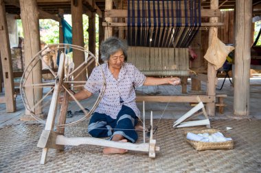 Tayland, Nan: 17 Kasım 2024 - Kuzey Tayland 'ın Nan ilindeki Wang Pha Köyü' ndeki Wat Nong Bua Müzesi 'nde geleneksel dokumada pamukla çalışan yaşlı kadın.  