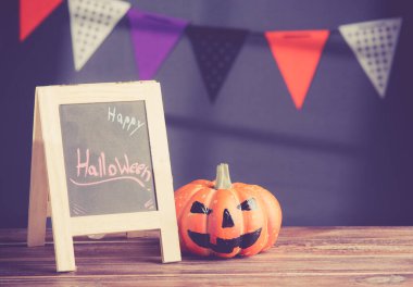 Halloween pumpkin head jack lantern and a chalkboard on wooden ; vintage tone style