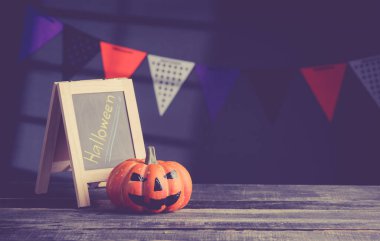 Halloween pumpkin head jack lantern and a chalkboard on wooden 