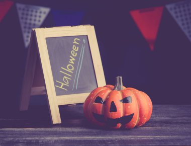 Halloween pumpkin head jack lantern and a chalkboard on wooden ; vintage tone style