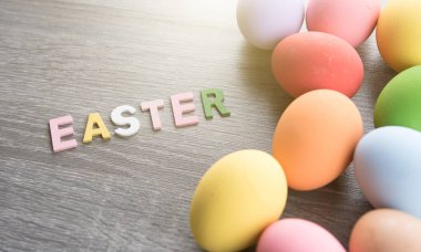 Easter eggs with EASTER word made from colored wooden letters on wood