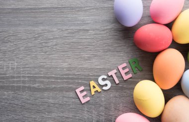 Easter eggs with EASTER word made from colored wooden letters on wood