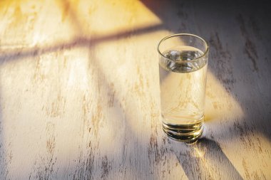 Refracted light from the window through the blinds in glass of water.