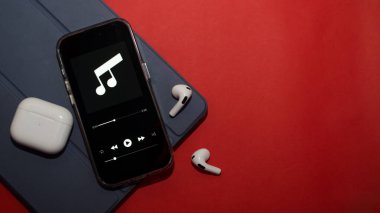 Telefon, kırmızı arkaplanda kulaklık, bir oyuncu ve metin için boş bir alan