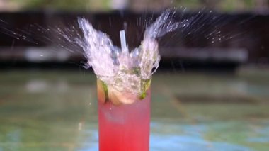 An ice cube is dipped into a glass with watermelon katel with cucumber slices and mint leaves, which are sprinkled with cold drops of a refreshing drink. Cold cocktail. Nice slow motion video.