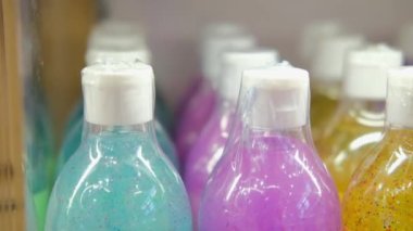 On the shelf of an eco store that sells ethical cosmetics and body care products, there are plastic bottles of various colors with shower gel cream made from natural ingredients.