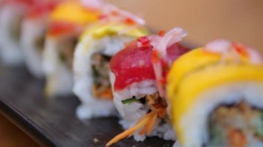 Close-up of vegetarian rolls wrapped in nori with rice and toppings on the outside. Rolls with vegetables and sauce cut into small pieces convenient for eating. Rolls on the restaurant table.