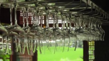 Clean glass glasses for various drinks hang above the bar. Glass glasses of various shapes hang on a shelf ready to be used in the restaurant bar. Looking forward to a festive evening.