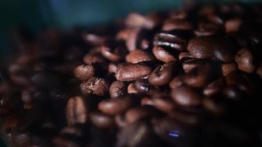 Coffee roasted beans of brightly saturated brown color close-up. The coffee lies in a storage container to be saturated with a deep aroma, a narrow beam of light falls on it.