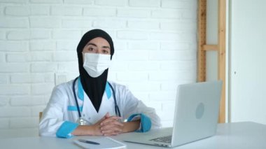 Koronovirüs salgını sırasında tesettürlü ve maskeli bir kadın doktor randevusunu gerçekleştirir. Müslüman bir kadın yakın geçmişte gelişmiş bir ülkede doktor olarak çalışıyor. Yüksek kalite 4k görüntü