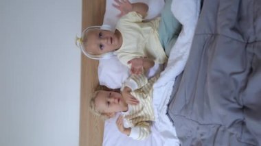 In the close-up video, the sisters are smiling. They perform a dance under the covers, moving their hands chaotically, as small children usually do. Music invigorates them. vertical video