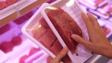 The customer selects fresh meat to prepare a delicious meal. High quality meat cut into portions in the form of steaks and laid out in plastic packaging for portions for cooking.