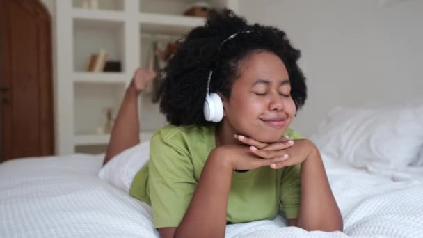 Śmieszna Czarna Kobieta Leży Łóżku Pokoju Słucha Muzyki Słuchawkach Tańcach — Wideo stockowe